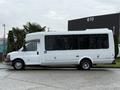 A white 2013 Chevrolet Express shuttle bus with large windows and a high roof is parked on a concrete surface
