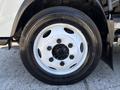 A close-up of the wheel of a 2022 Isuzu NRR featuring a white rim and black tire with visible bolts around the hub