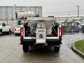 A 2023 Ford F-250 truck with a mounted spreader in the bed displaying the Fisher logo