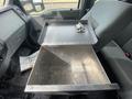 A metal storage compartment is open inside a 2014 Ford F-350 SD truck with a locking mechanism visible