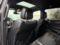 Interior view of a 2019 Jeep Grand Cherokee showcasing black leather seats and a sunroof with rear passenger seating area visible
