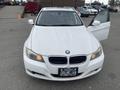 A white 2011 BMW 3-Series with a partially open driver's door and visible headlights
