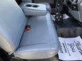 A grey leather seat with a center armrest and a cup holder in a 2017 Ford F-650 Super Duty truck's cabin