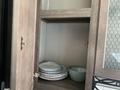 A wooden cabinet with stacked plates and a bowl inside