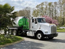A white 1996 Kenworth T800 truck with a green tank on its flatbed, featuring a large chrome grille and dual exhaust pipes