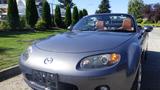 A 2007 Mazda Miata with a sleek gray exterior and tan leather seats, featuring a convertible roof and a sporty design