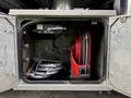 A compartment in a truck featuring a red retractable hose reel and two gray hoses neatly coiled inside