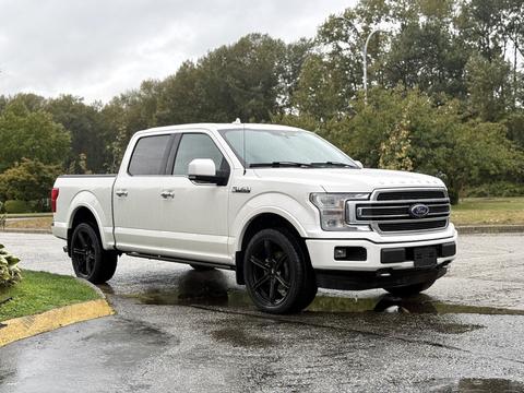 A white 2018 Ford F-150 with black wheels parked on a wet surface showcasing its sleek design and modern pickup features