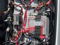 A close-up of the wiring and electrical components inside a 2013 Chevrolet Express with various colored wires and a fuse box