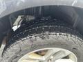 A close-up of a 2016 Ford Explorer tire with a rugged tread pattern showing water droplets on its surface and the wheel partially visible in the frame