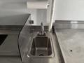 A stainless steel sink with hot and cold water taps is prominently featured in the foreground