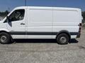 A white 2016 Mercedes-Benz Sprinter van is parked with a plain side profile showing its sliding door and black trim along the base. The vehicle has no visible branding or markings