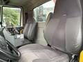Interior of a 2012 International 7400 showing two gray fabric seats and a dashboard console with controls and a warning label
