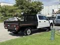 A white 2020 Ford F-350 SD truck with a flatbed and black metal railing parked in a lot