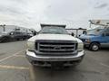 A 2004 Ford F-350 SD with a worn white exterior and a large front grille parked in a lot