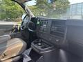 Interior view of a 2021 Chevrolet Express focusing on the driver's seat dashboard and central console with controls and cup holders