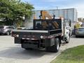 A 2011 International 4300 truck with a flatbed featuring safety rails and orange traffic cones on the top