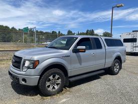 A silver 2014 Ford F-150 with a truck bed cover parked at an angle displaying its front and side features