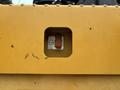 A close-up of a yellow panel from a 2012 Caterpillar 980 showing a rectangular slot with a lever and a label indicating a stop function