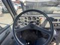 The interior of a 1997 Freightliner FL70 showing the steering wheel dashboard gauges and control buttons