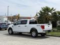 A white 2021 Ford F-150 truck parked at an angle revealing the side and rear design features including a 4x4 emblem and chrome accents