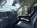 Interior of a 2025 Ford Transit T-350 showing the driver's seat steering wheel and dashboard with controls and a fabric seat