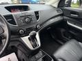 Interior of a 2014 Honda CR-V featuring a modern dashboard with control buttons a gear shift and leather seats