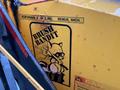 A yellow Brush Bandit machine with a raccoon cartoon logo and safety warning labels