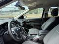 Interior of a 2015 Ford Escape featuring front seats with gray upholstery a steering wheel and center console with gear shift and cup holders