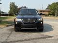 A black 2013 BMW X3 is parked with its front view facing the camera showcasing its distinct kidney grille and headlights
