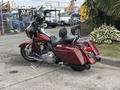 A 2009 Harley-Davidson Road King motorcycle in a deep burgundy color with chrome accents and a comfortable seat parked on a concrete surface