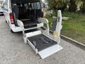 A 2009 Toyota Hiace with a wheelchair lift extended on the side showing the ramp and support handles