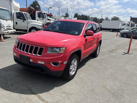 A red 2015 Jeep Grand Cherokee parked with its front angled slightly to the right showcasing its distinctive grille and wheel design