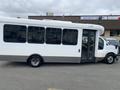 A white 2020 Chevrolet Express bus with large windows and a door at the front is parked with its body at an angle visible from the side