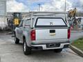 A silver 2018 Chevrolet Colorado with a canopy and ladder rack attached to the bed, parked with the back facing the viewer