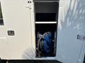 A blue hose reel with several coils is stored inside a compartment of a 2006 Sterling Acterra vehicle