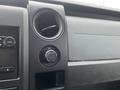 Interior view of a 2013 Ford F-150 dashboard showing audio controls an air vent and a 12V power outlet