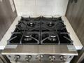 A modern gas stove with four burners and metal grates in a kitchen setting