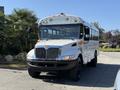 A 2013 International CE300 school bus with a white body and black front bumper parked on a driveway
