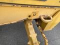 A close-up view of a 2012 John Deere 310SJ showcasing its rusty yellow metal body with a hydraulic cylinder and a safety warning symbol