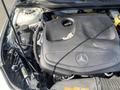The engine compartment of a 2014 Mercedes-Benz CLA-Class showing the engine cover with the Mercedes-Benz logo and various engine components and fluid reservoirs