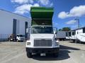 A front view of a white 1997 Freightliner FL70 truck with a green dump bed raised in the air