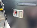 A close-up view of a chrome switch panel with a red lever on a black surface inside a 2020 Freightliner MT45