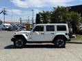 A white 2021 Jeep Wrangler Rubicon parked with a side view showcasing its rugged design and off-road capabilities