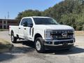 A 2023 Ford F-350 Super Duty in white with chrome accents parked on a concrete surface showcasing its large truck body and four wheels
