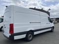 A 2025 Mercedes-Benz Sprinter van with a white body and black lower section featuring a large cargo area and standard wheels