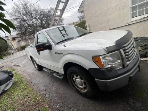 A white 2011 Ford F-150 pickup truck angled to the left with a single cab and distinctive grille design