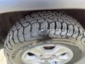 A close-up view of the tire of a 2015 Jeep Grand Cherokee showing a rugged tread pattern designed for off-road performance