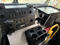 The interior dashboard of a 2017 Freightliner MT45 featuring various controls switches a cup holder and a compartment for storage