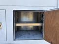 Metal storage compartment with one shelf visible inside and a wooden door on the right side